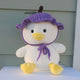 A duck plushie wearing a purple grape shaped crochet hat with a green leaf and a brown steam on top of the hat